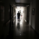 A cancer patient pushes his drip stand as he walks down the hallway of a hospital in Beijing